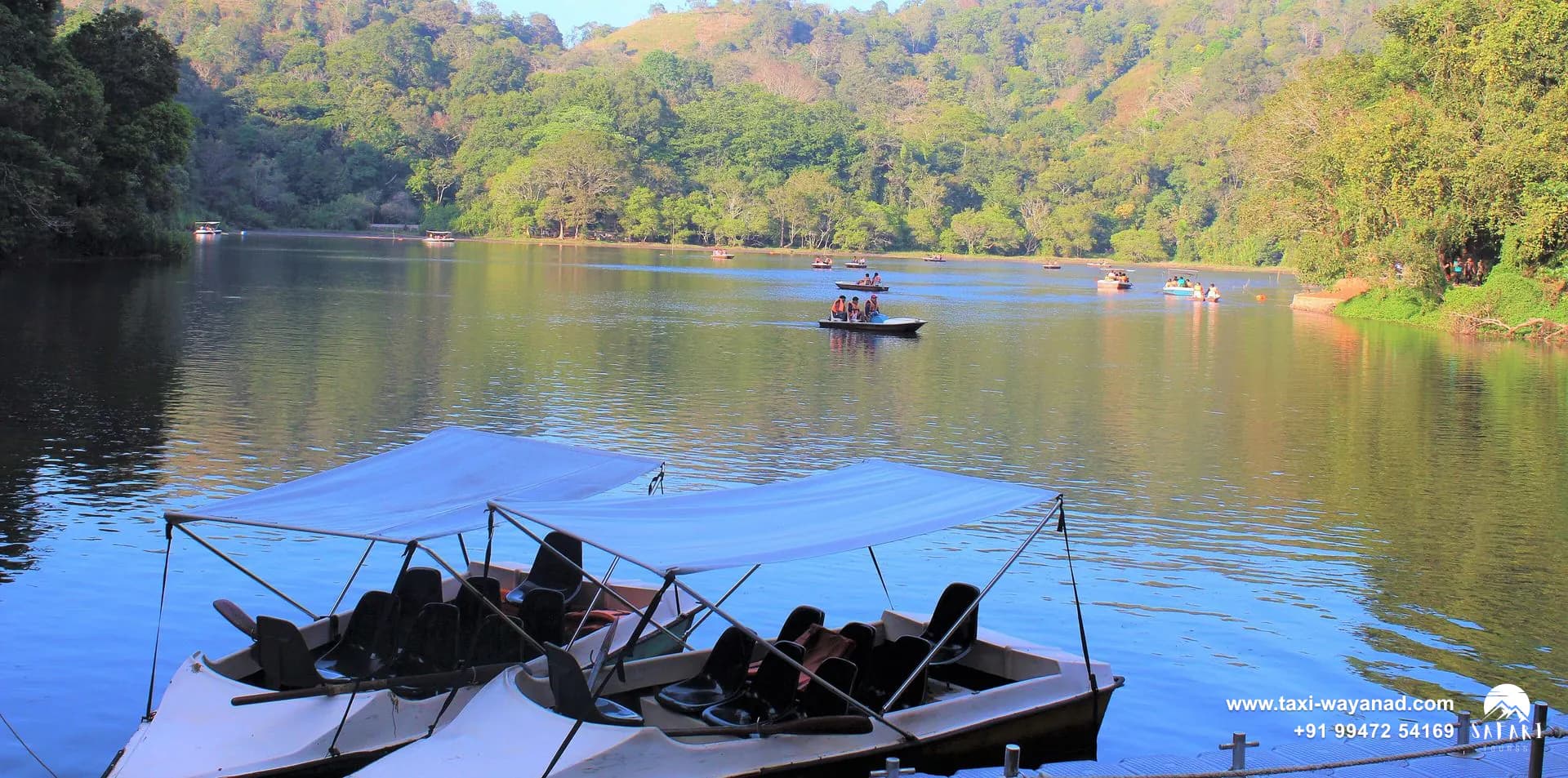 Pedal boats moored in front of forested hills at Pookode Lake, Wayanad