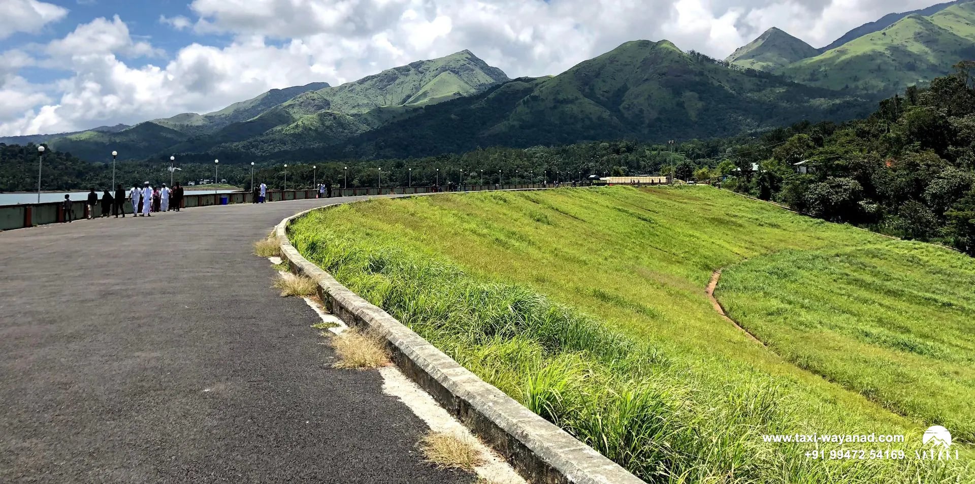 Road along the top of Banasura Sagar Dam beside its grassy embankment below the Banasura hills, Wayanad