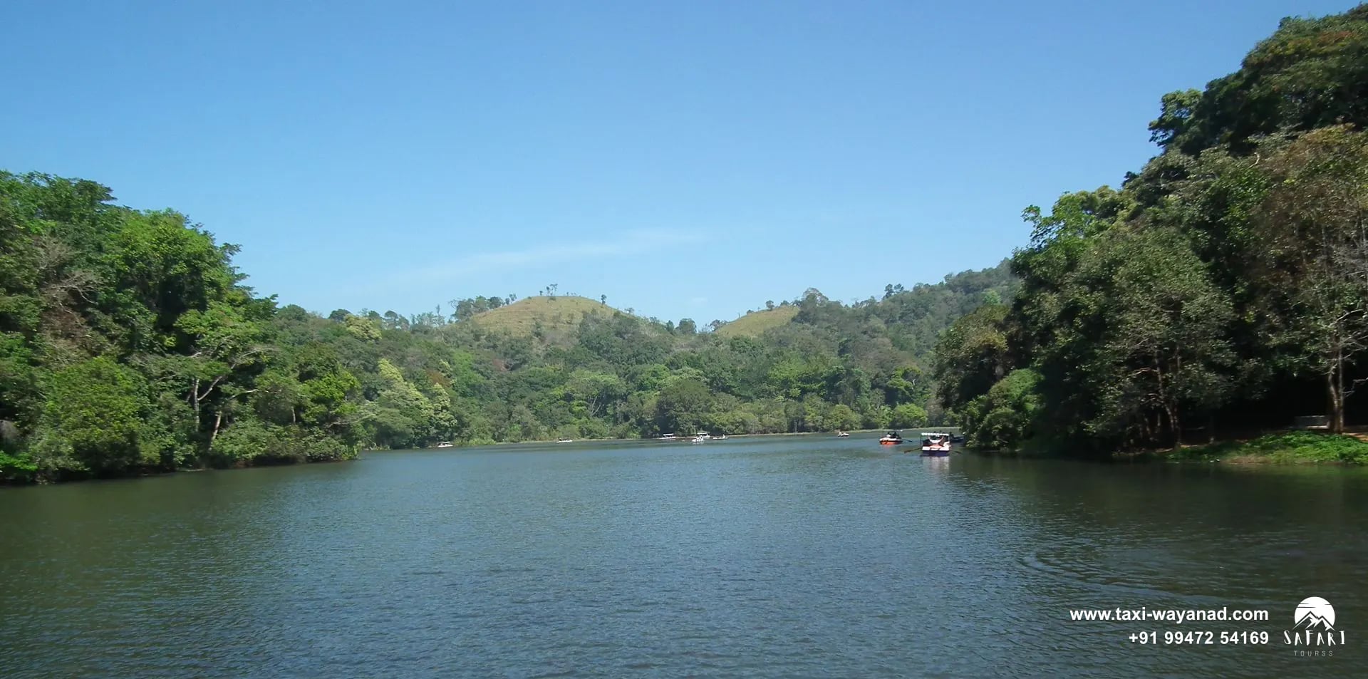 Calm water stretching between evergreen forested shores at Pookode Lake, Wayanad