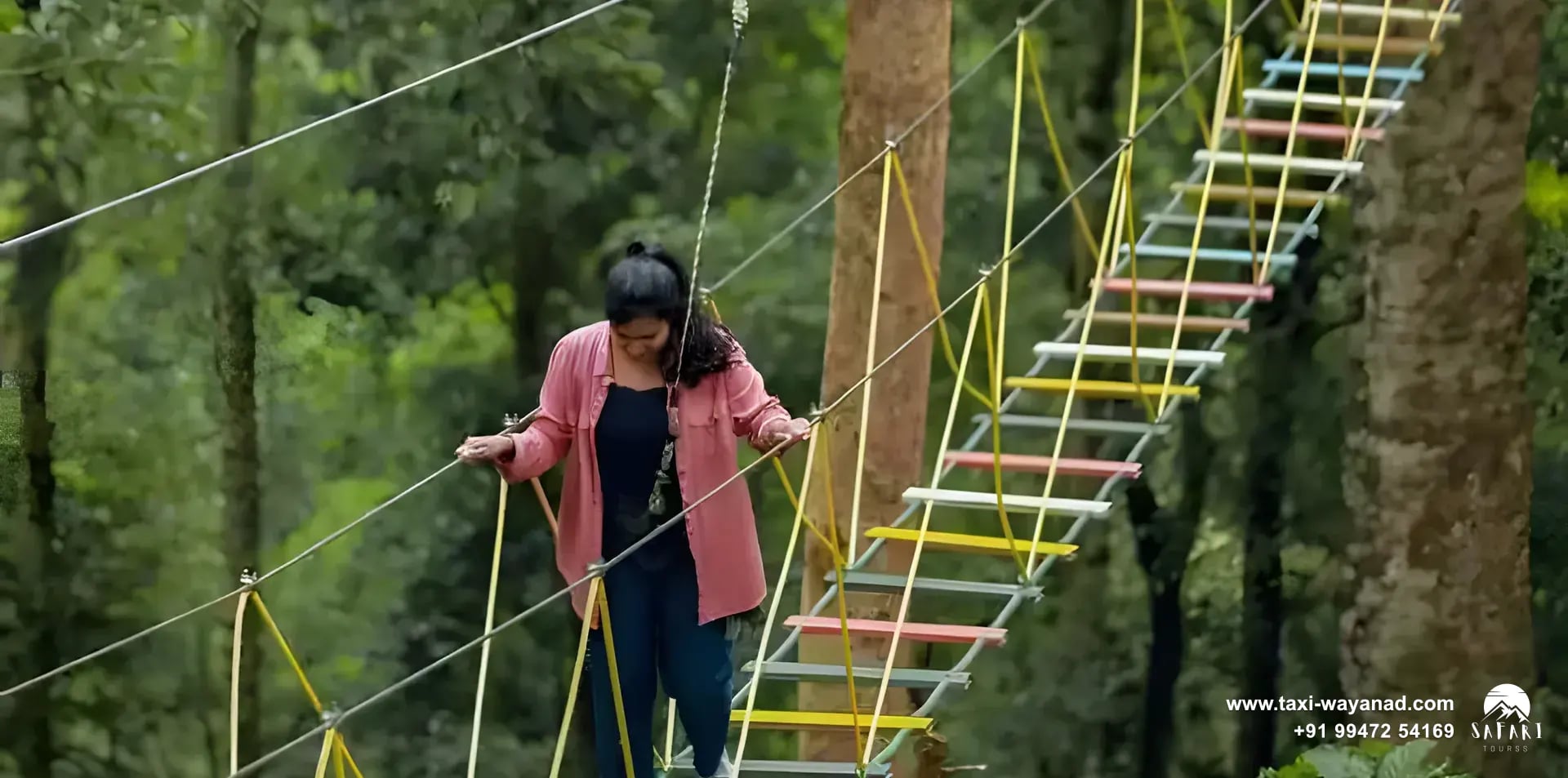 Visitor crossing a rope ladder bridge in the 900 Kandi forest, Wayanad