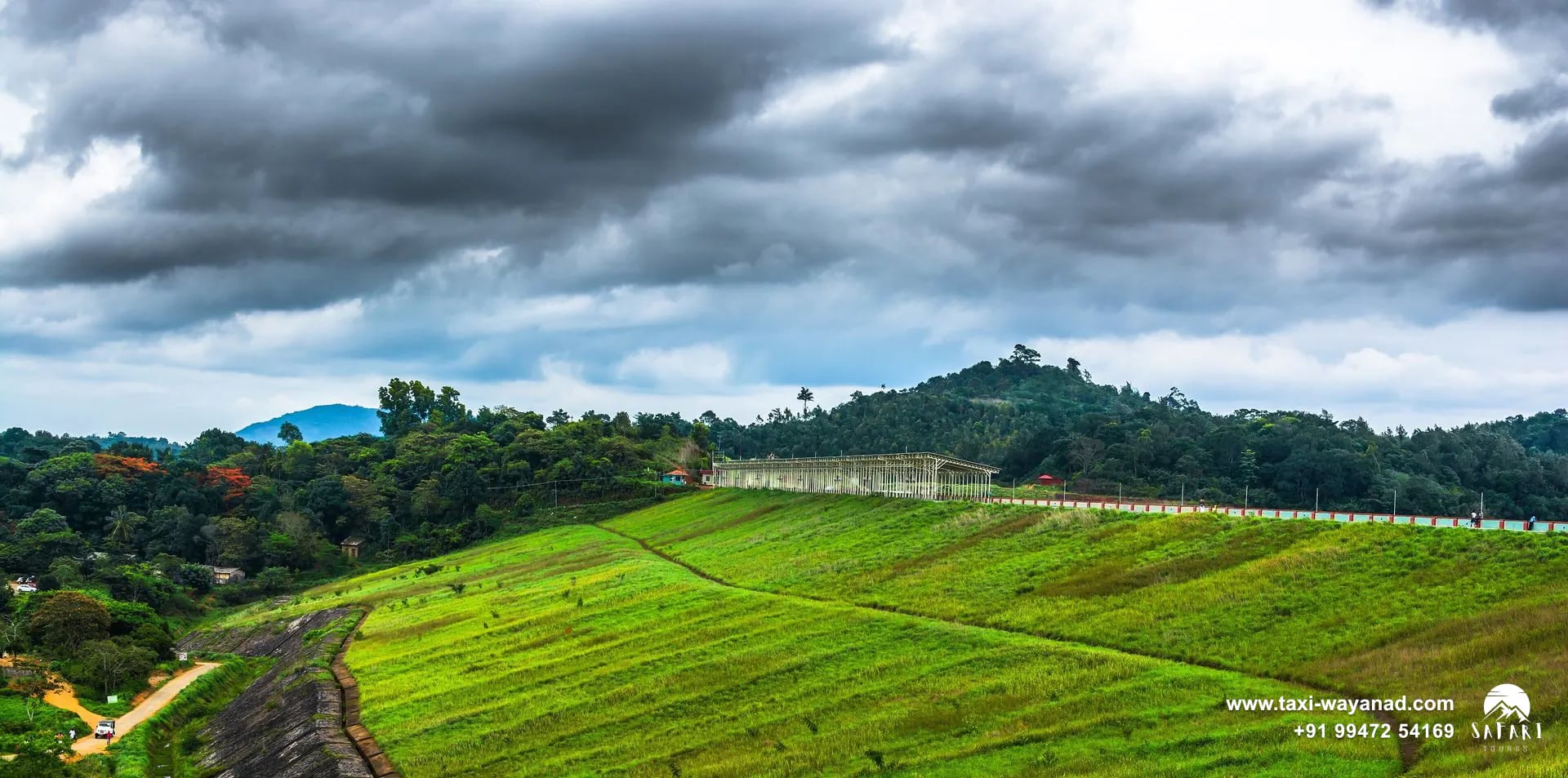 Green grassy earthen embankment of Banasura Sagar Dam under monsoon clouds, Wayanad