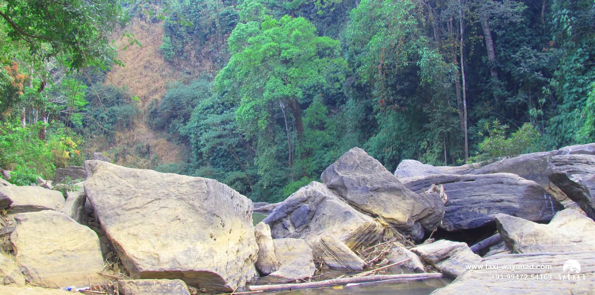 Boulder-strewn stream bed and dense forest near Kanthanpara Waterfalls, Wayanad