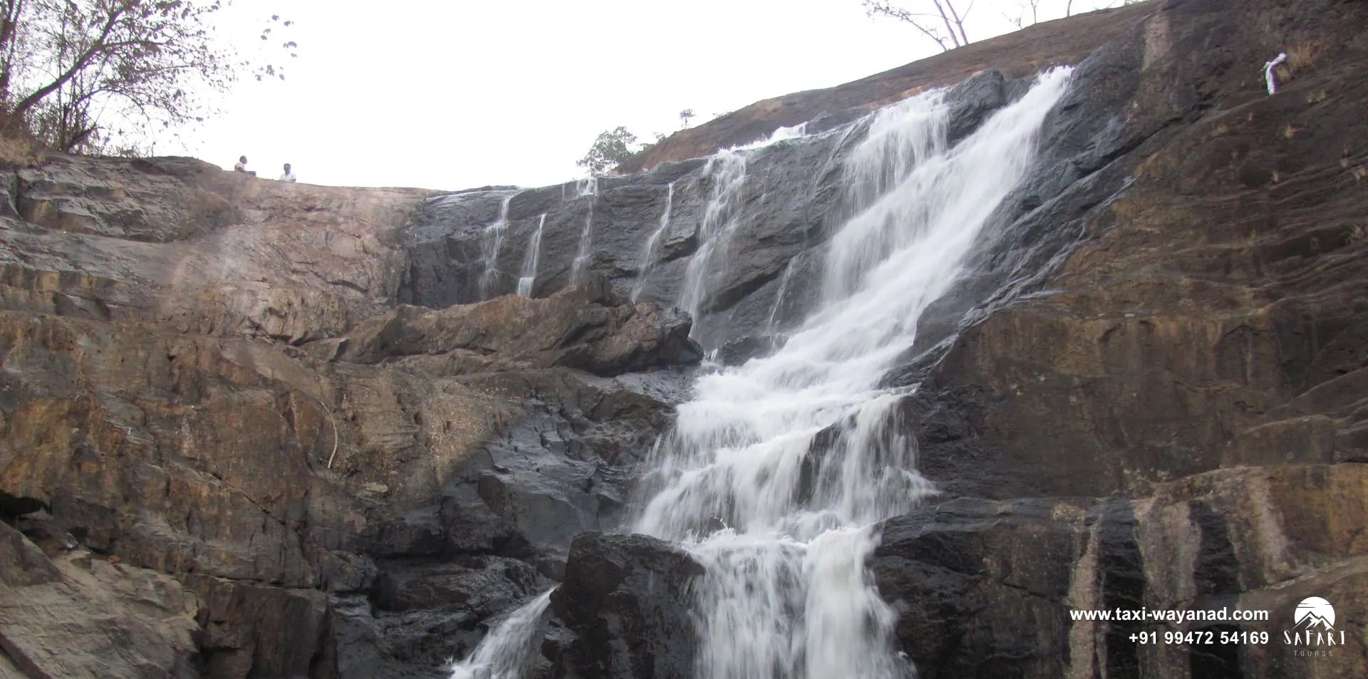 Kanthanpara Waterfalls spilling down a wide dark rock face, Wayanad