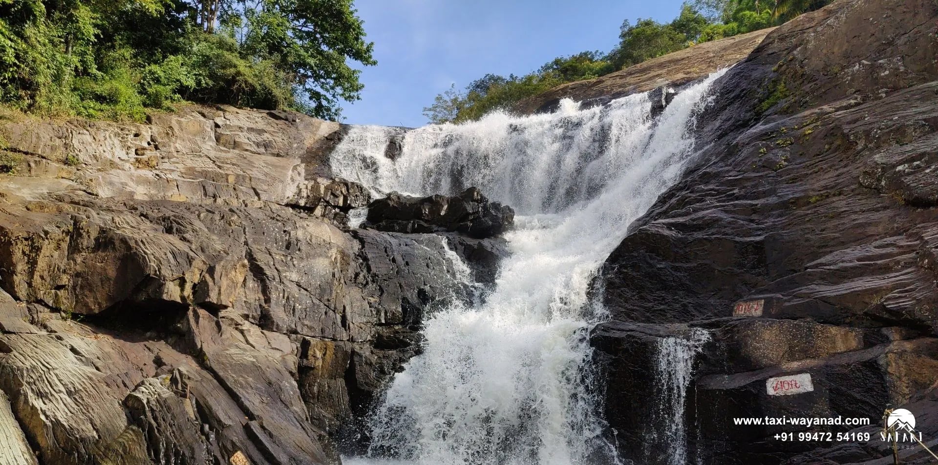 Kanthanpara Waterfalls cascading in tiers over dark sloping rock into a pool, Wayanad