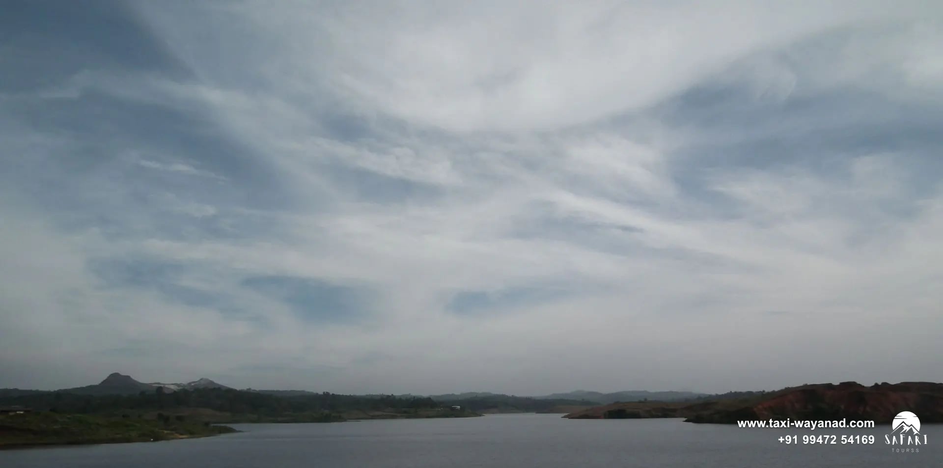 Spillway gates and outlet channel below the grassy embankment of Karapuzha Dam, Wayanad