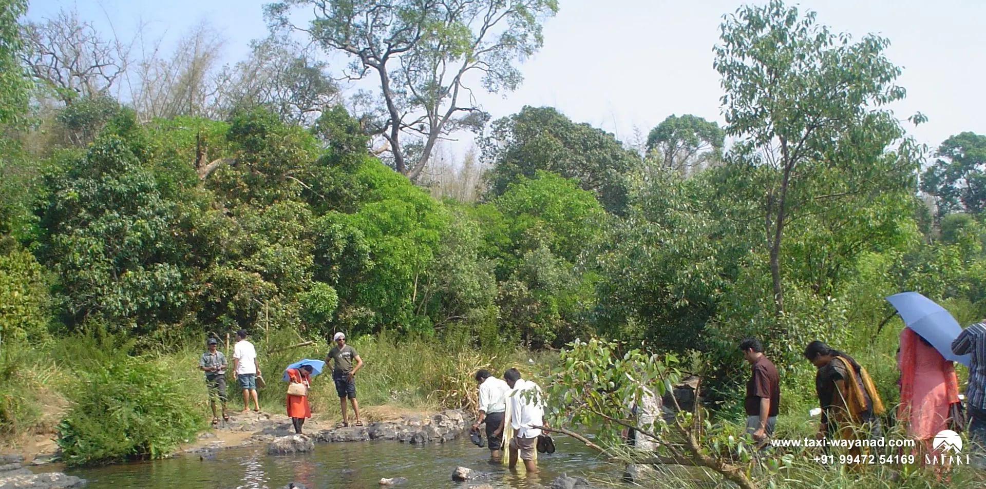 Visitors wading through the rocky shallows of the Kabini River at Kuruva Island, Wayanad