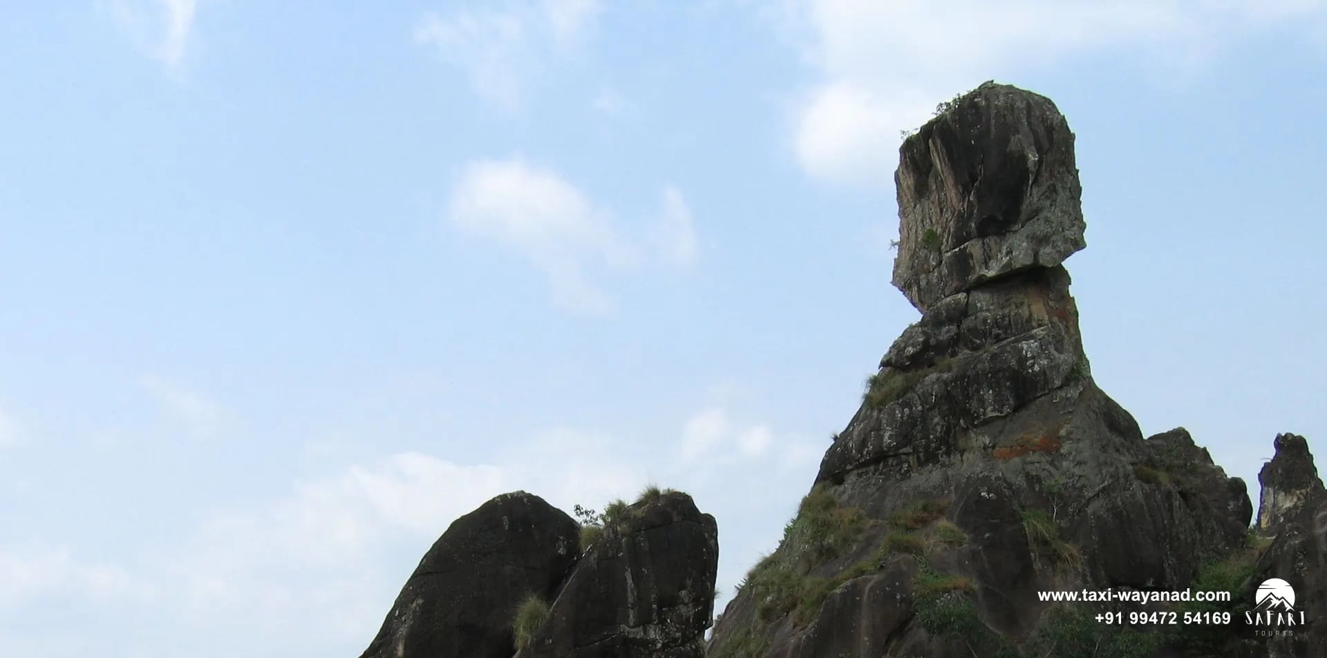 Phantom Rock balanced on top of a large granite outcrop under a blue sky, Wayanad