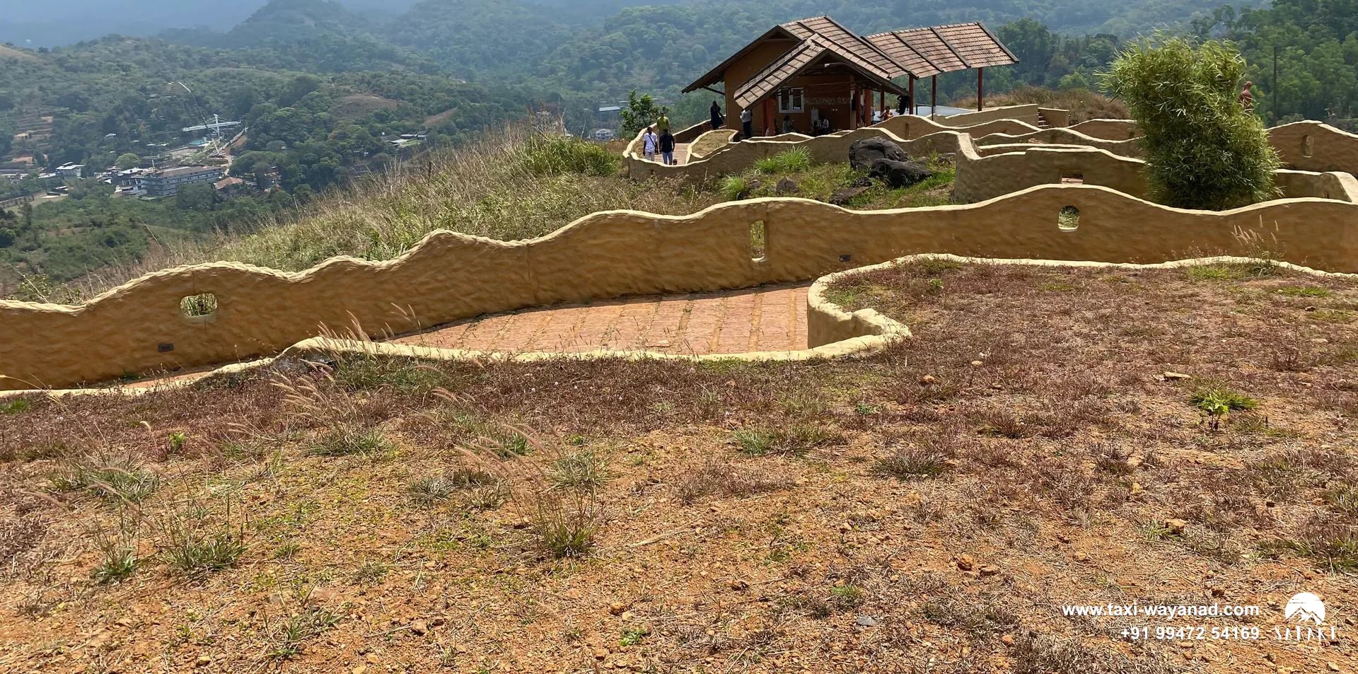 Hilltop hut and winding mud-walled paths overlooking the hills at En Ooru tribal village, Wayanad